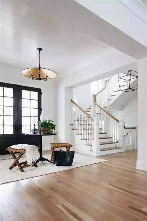 White entry with shiplap ceiling, black French doors, woven stools, wood stair
