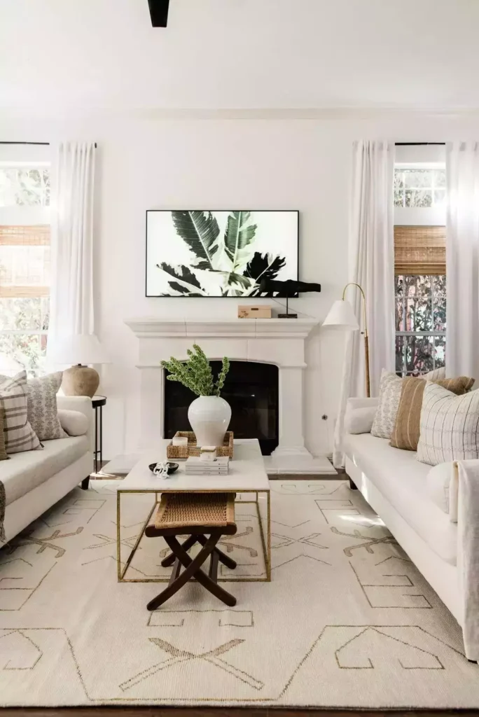 White mantel living room, banana-leaf art, facing sofas, marble-and-brass table