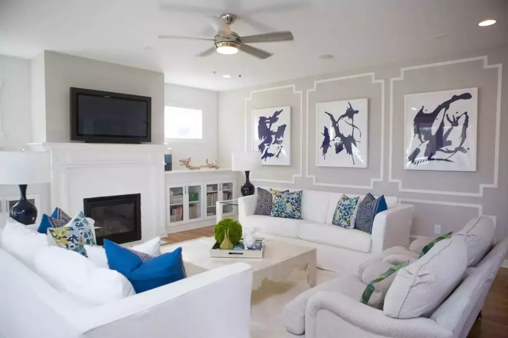 White paneled living room, ink-blot art, cobalt pillows, white fireplace