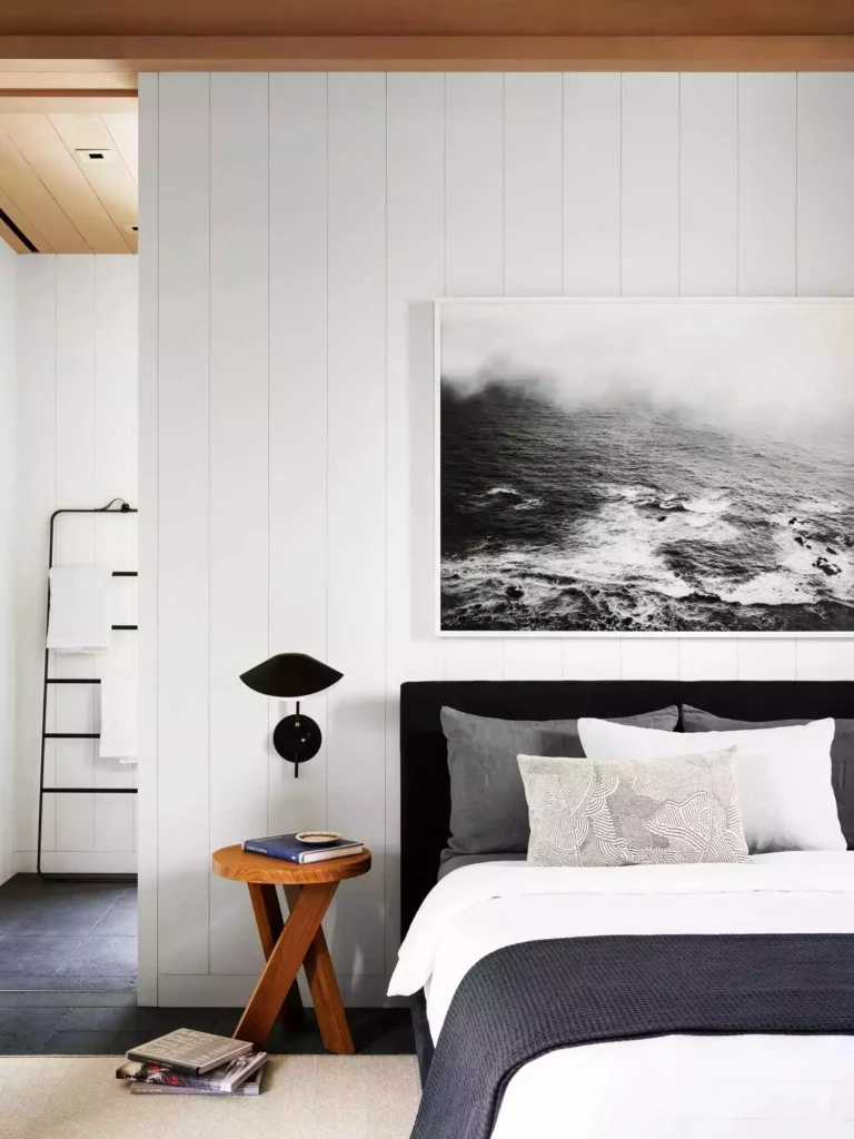 White shiplap bedroom wall, stormy seascape, black headboard, sculptural sconce