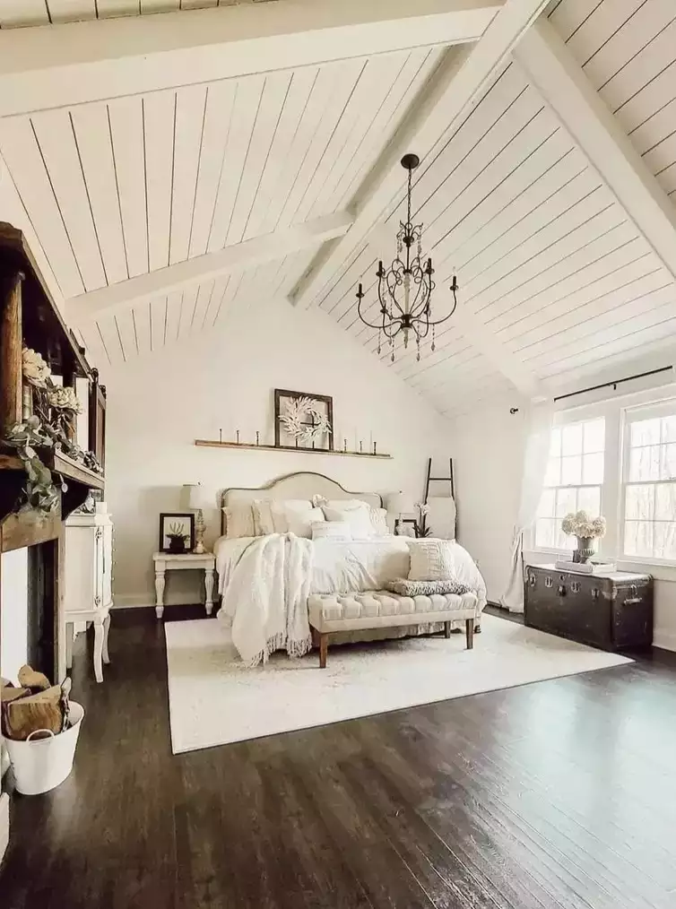 White shiplap vaulted bedroom, iron chandelier, tufted bench, vintage trunk