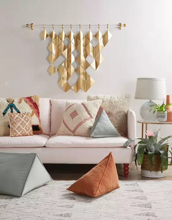 White sofa beneath hanging gold diamonds on the above sofa wall