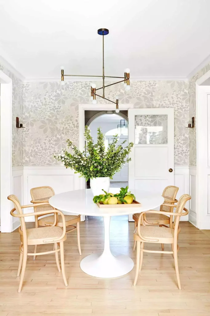 White wainscot dining room, floral wallpaper, tulip table, cane chairs