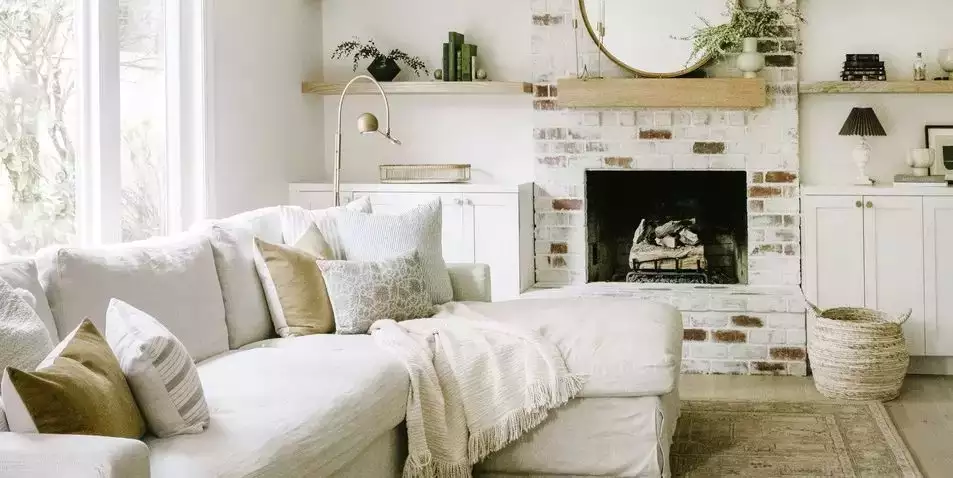 Whitewashed brick fireplace, oak shelves, cream chaise, woven basket
