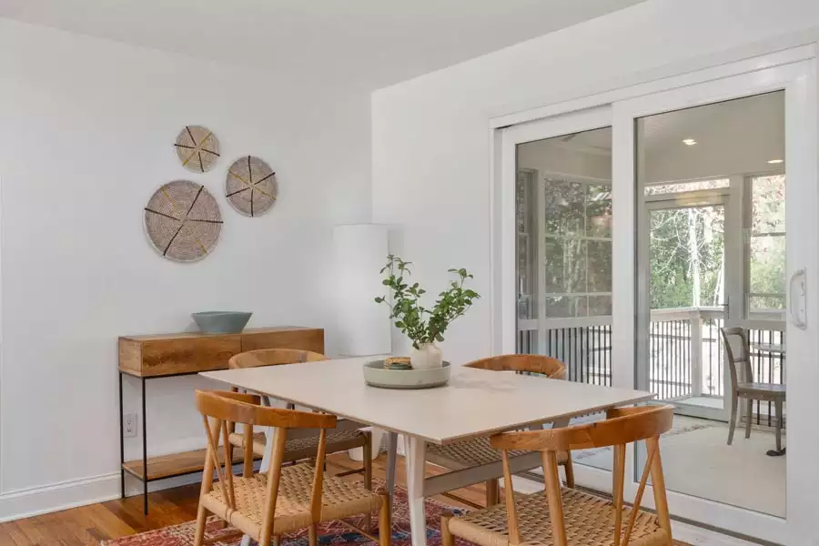 Woven basket plates on a white wall provide simple boho Dining Wall Decor beside a wood console and light dining table