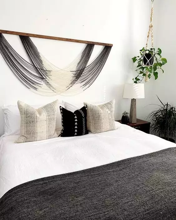 Woven fringe macrame hanging as boho over the bed wall decor above black and white pillows