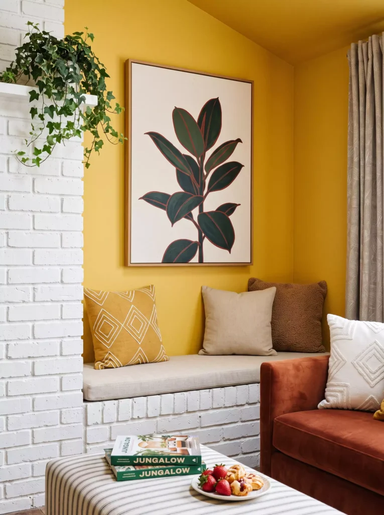 Cozy reading nook with yellow wall, botanical artwork, plants, and comfortable seating
