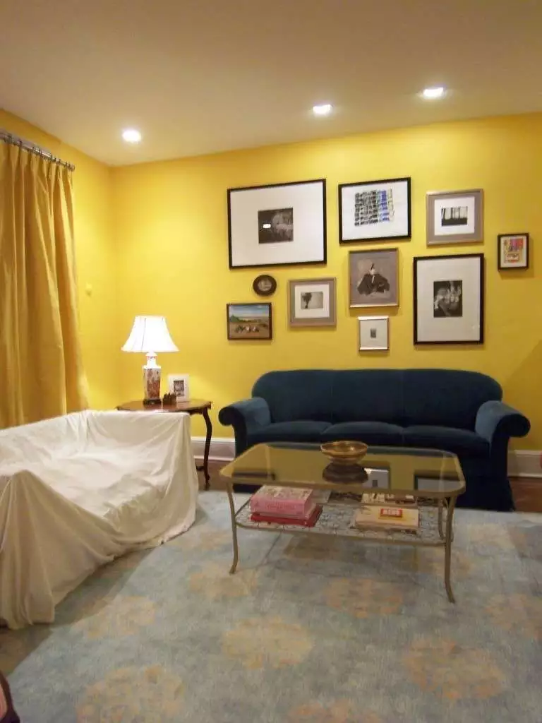 Warm yellow living room with gallery wall, dark sofa, and layered lighting