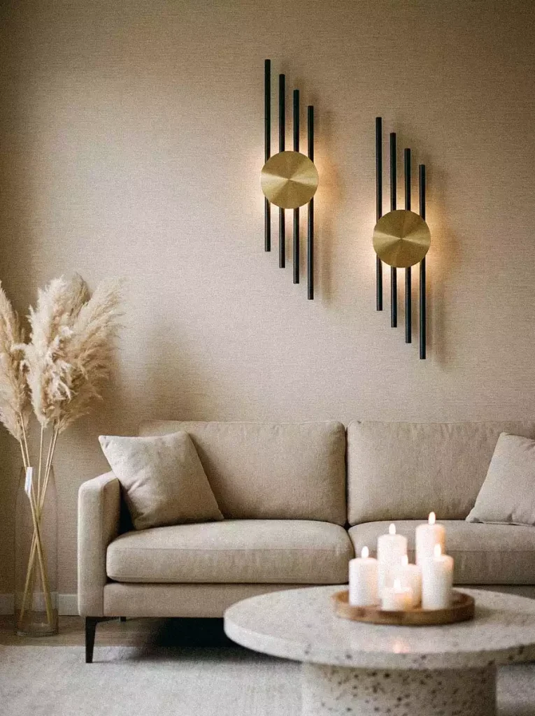 Black-and-gold geometric wall lights above a cream sofa and candle-filled coffee table