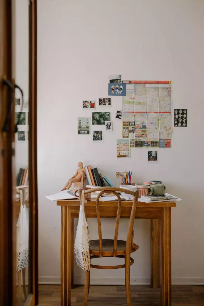 City Map And Small Photographs Above A Wooden Study Desk With A Curved Back Chair