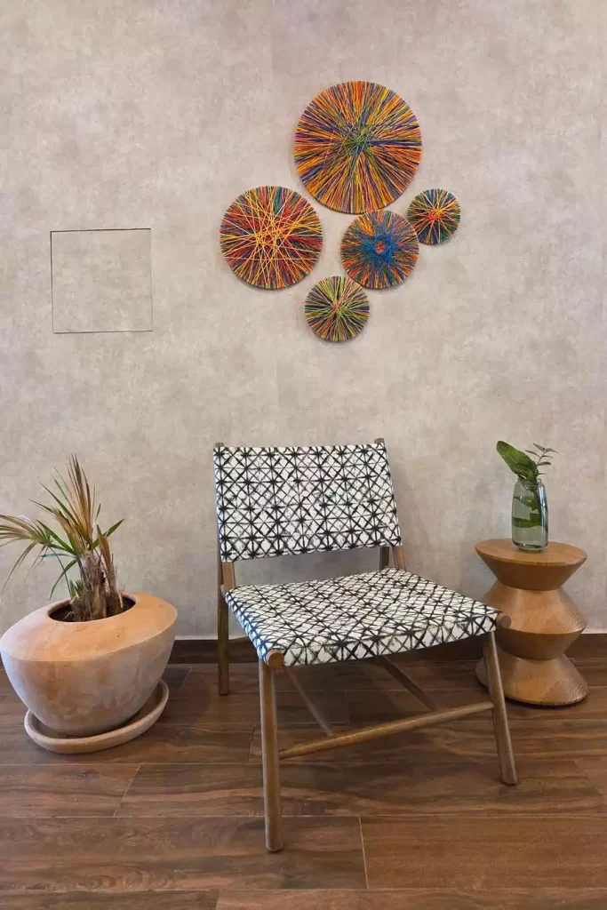 Colorful circular string wall art above a black-and-white patterned chair