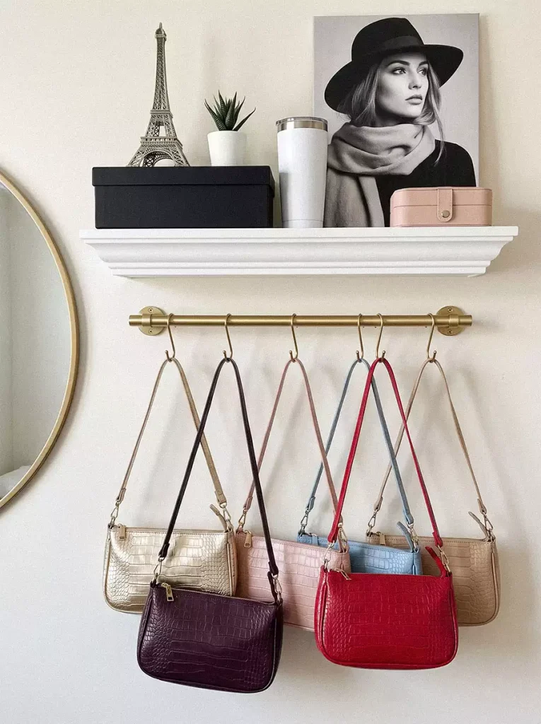 Colorful shoulder bags hanging from a brass rail beneath a white display shelf