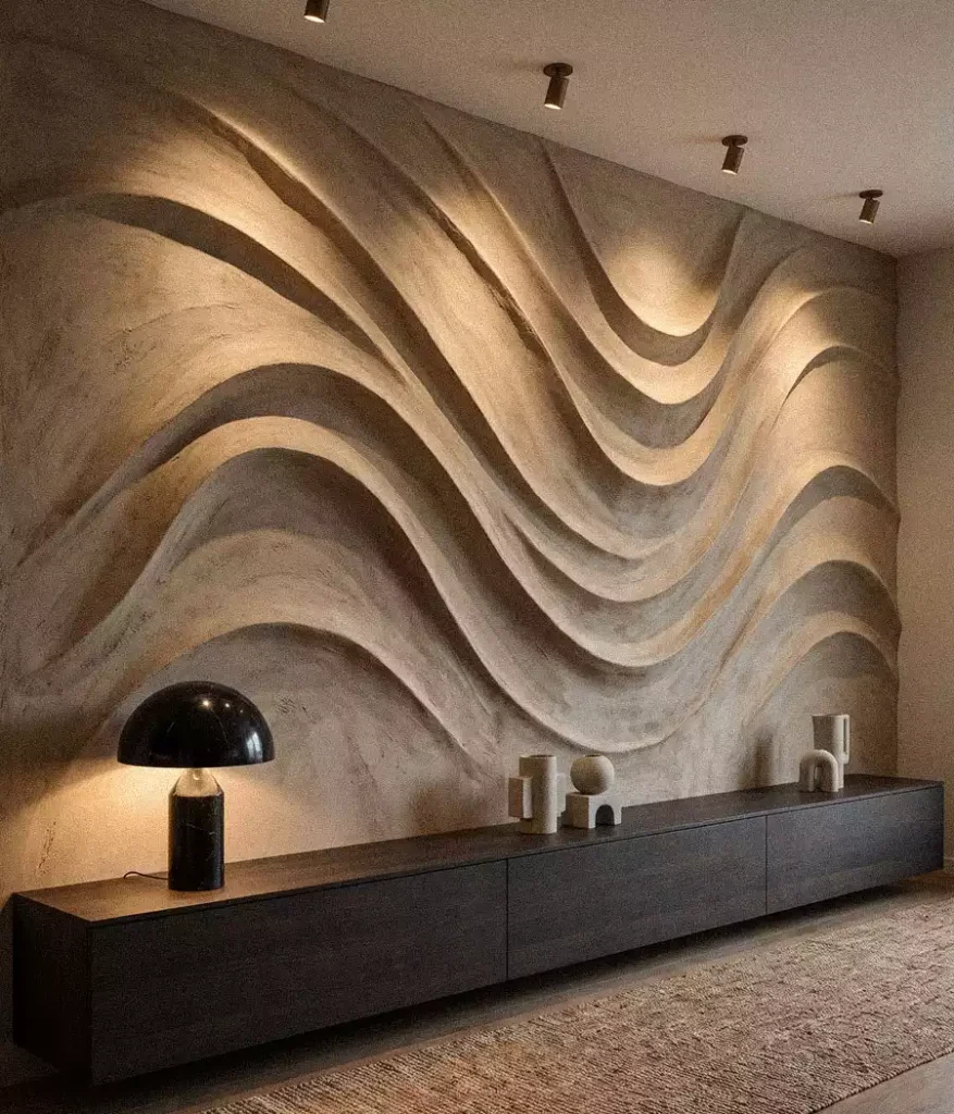 Deep flowing wall relief above a long dark cabinet with a table lamp and ceramics