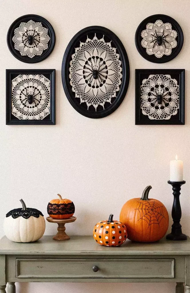 Framed white lace doilies with black spiders above a console displaying decorated pumpkins