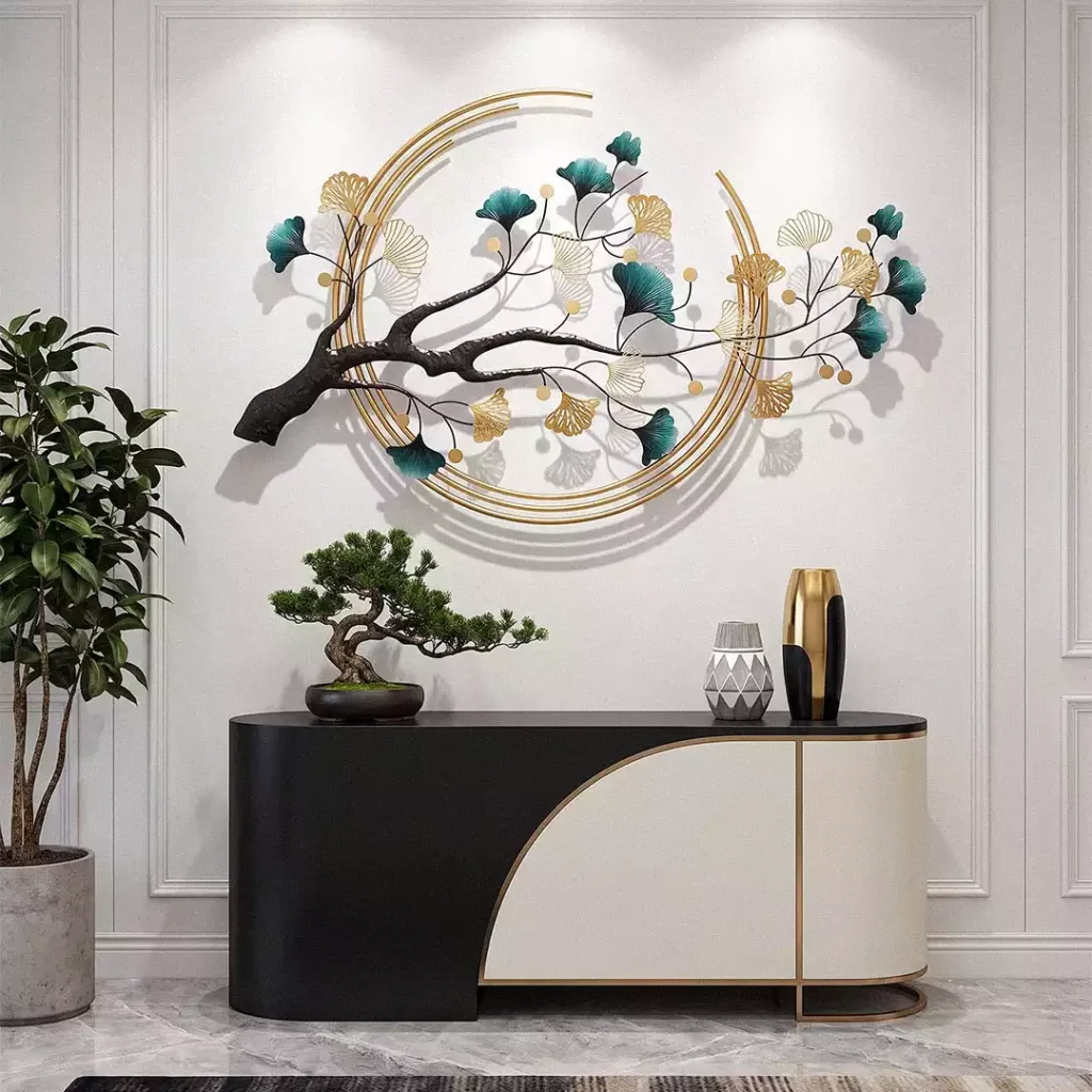Ginkgo wall sculpture with teal and gold leaves and gold rings above a console