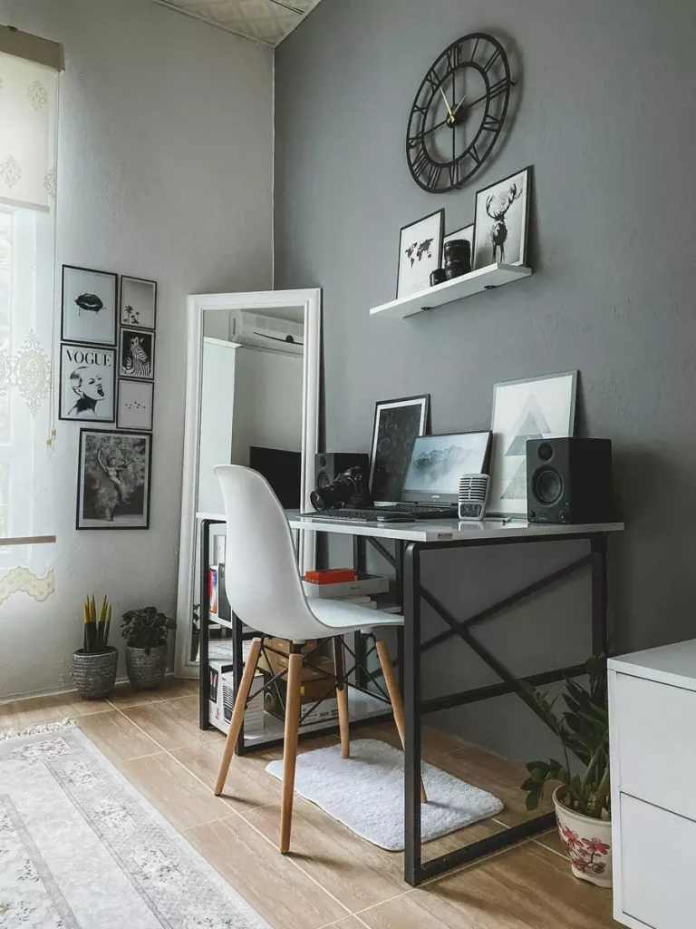 Gray Study Wall With A Large Clock And White Picture Ledge Above A Desk With A White Chair