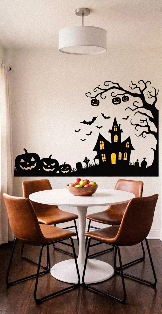 Halloween wall decor featuring a haunted house, bare tree, bats, and jack-o’-lanterns beside a dining table