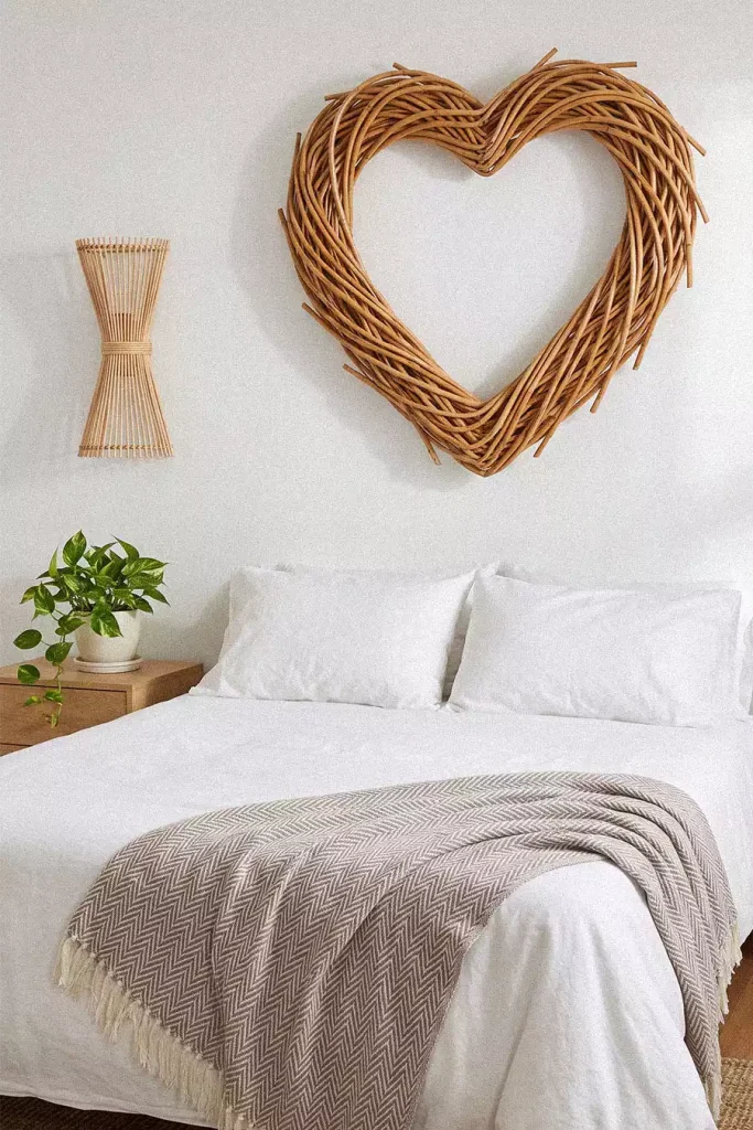 Heart shaped rattan wreath above white bed