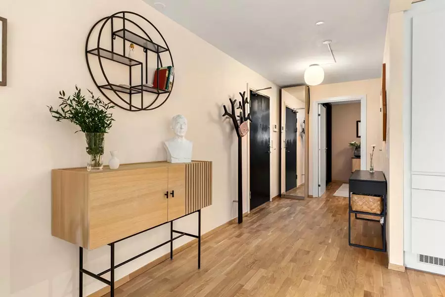 Large circular black wall shelf above a light wood cabinet with a leafy vase and white sculptural bust