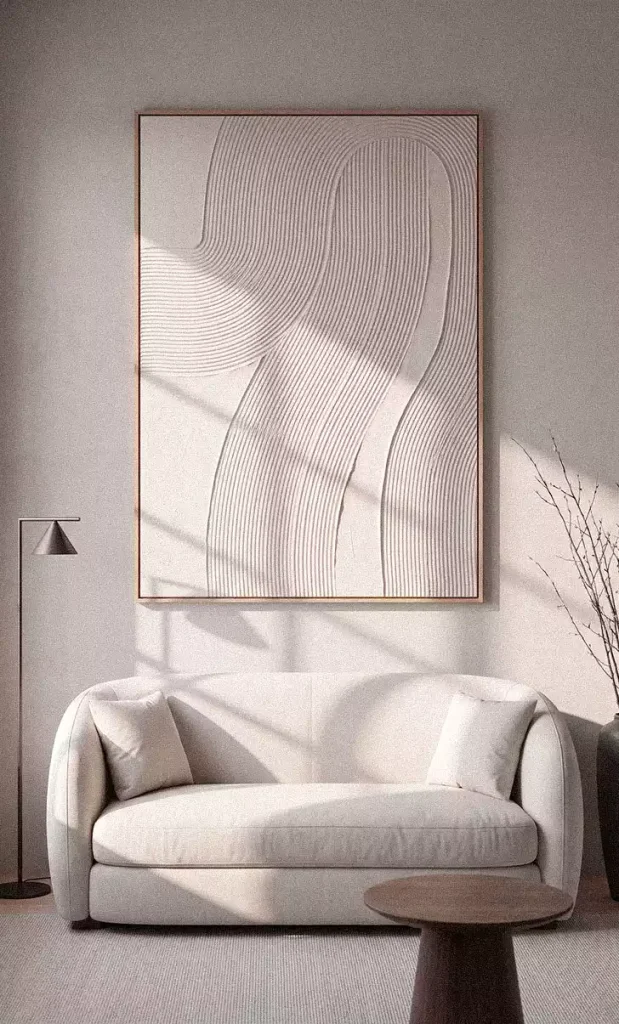 Large framed white relief with fine curved lines above a cream loveseat