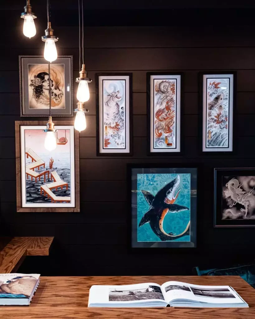 Marine-themed gallery wall decor displays shark, octopus, and wave illustrations on a dark paneled wall beneath exposed hanging bulbs