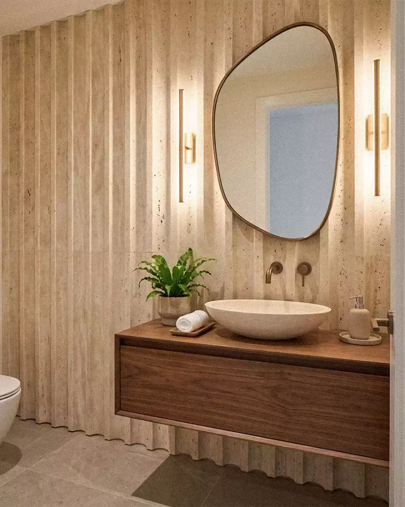 Modern bathroom with fluted travertine wall panels, floating walnut vanity, stone vessel sink, and bronze mirror