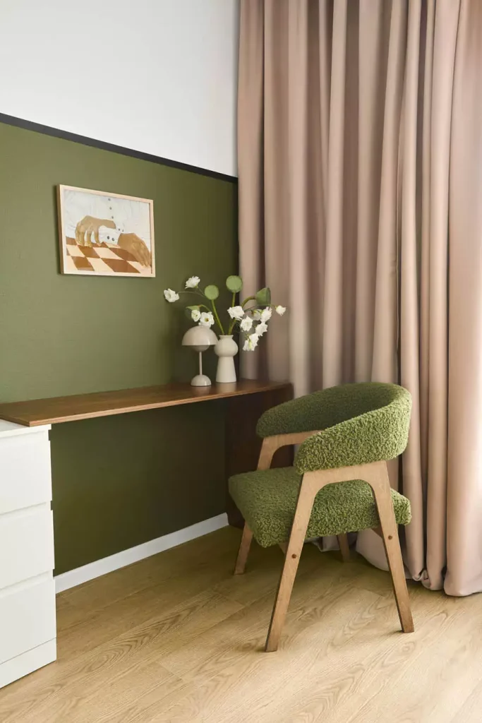 Olive Green Study Wall With A Small Framed Print Above A Narrow Wooden Desk And Green Upholstered Chair
