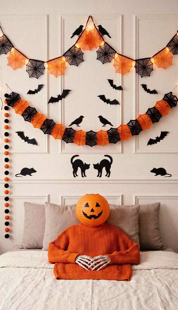 Orange and black spiderweb garlands with bat, crow, cat, and mouse silhouettes above a bed