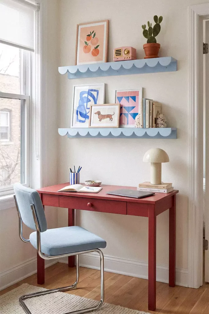 Pale blue scalloped wall shelves displaying framed prints, a pink radio, and a cactus
