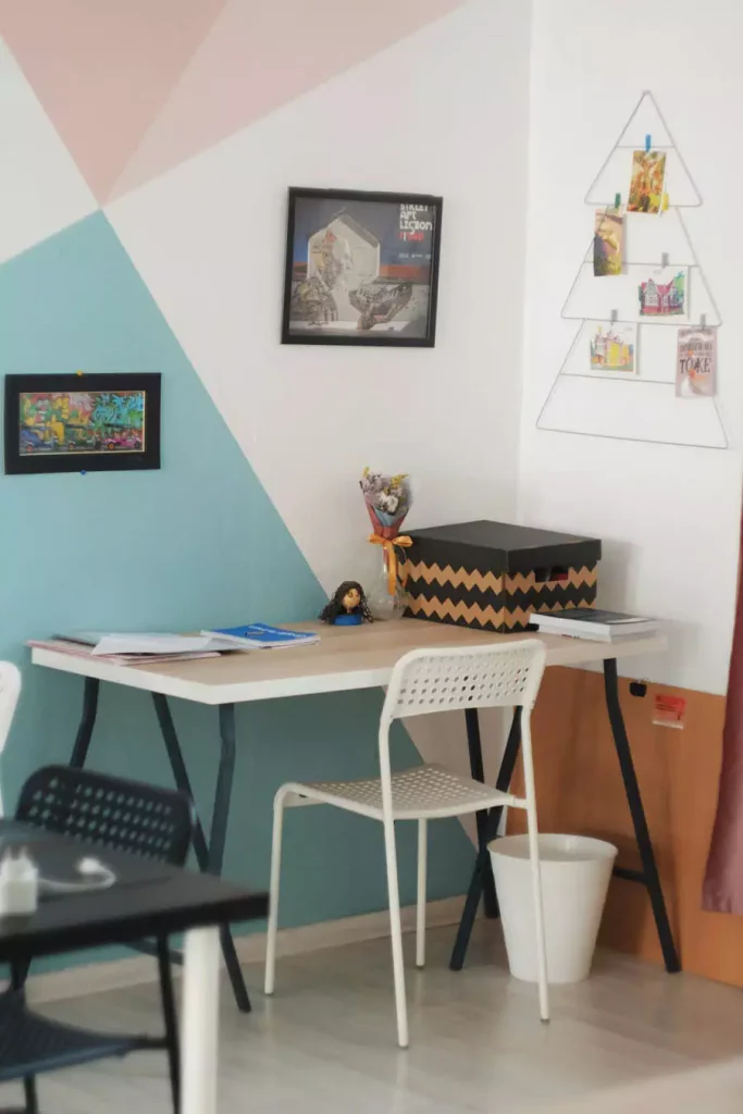 Pastel Geometric Study Wall With Framed Pictures And A Triangular Wire Photo Display Above A Desk