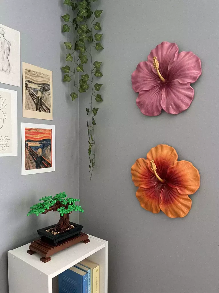 Pink and orange hibiscus wall sculptures on a gray wall