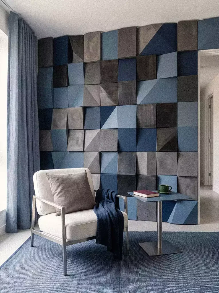 Raised blue and grey geometric wall panels behind a cream reading chair