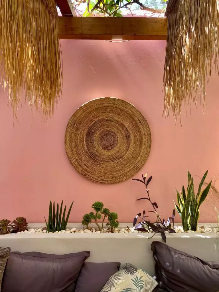 Round woven wall hanging on pink patio wall