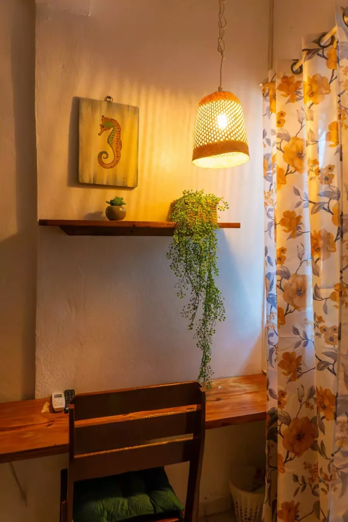 Seahorse Wall Art And A Floating Plant Shelf Above A Wooden Study Desk Beside A Woven Pendant Light