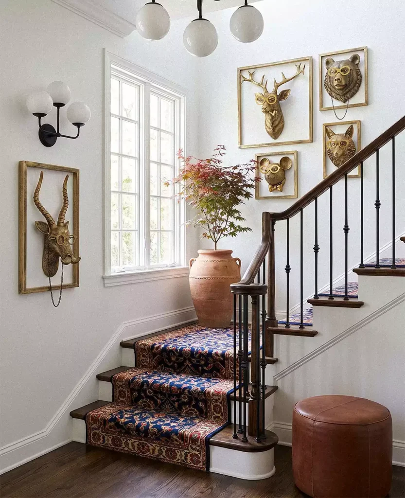 Staircase gallery wall with framed gold animal heads wearing decorative glasses