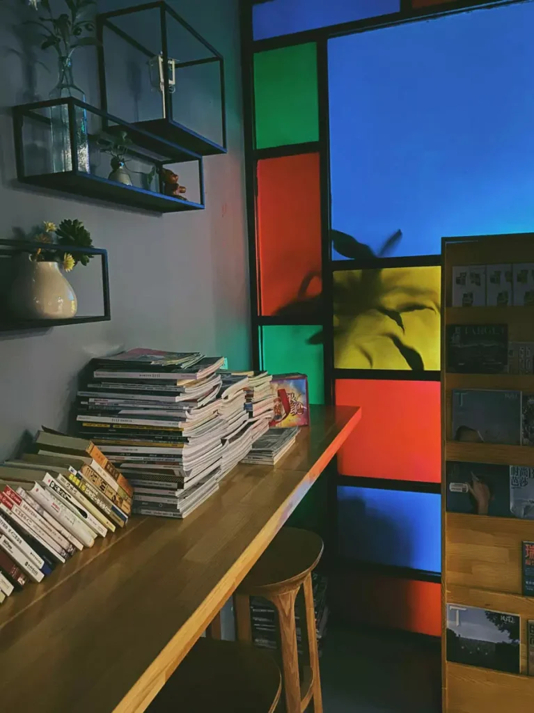 Study Corner With Wall Shelves And A Colorful Geometric Partition Beside A Wooden Worktop Stacked With Books