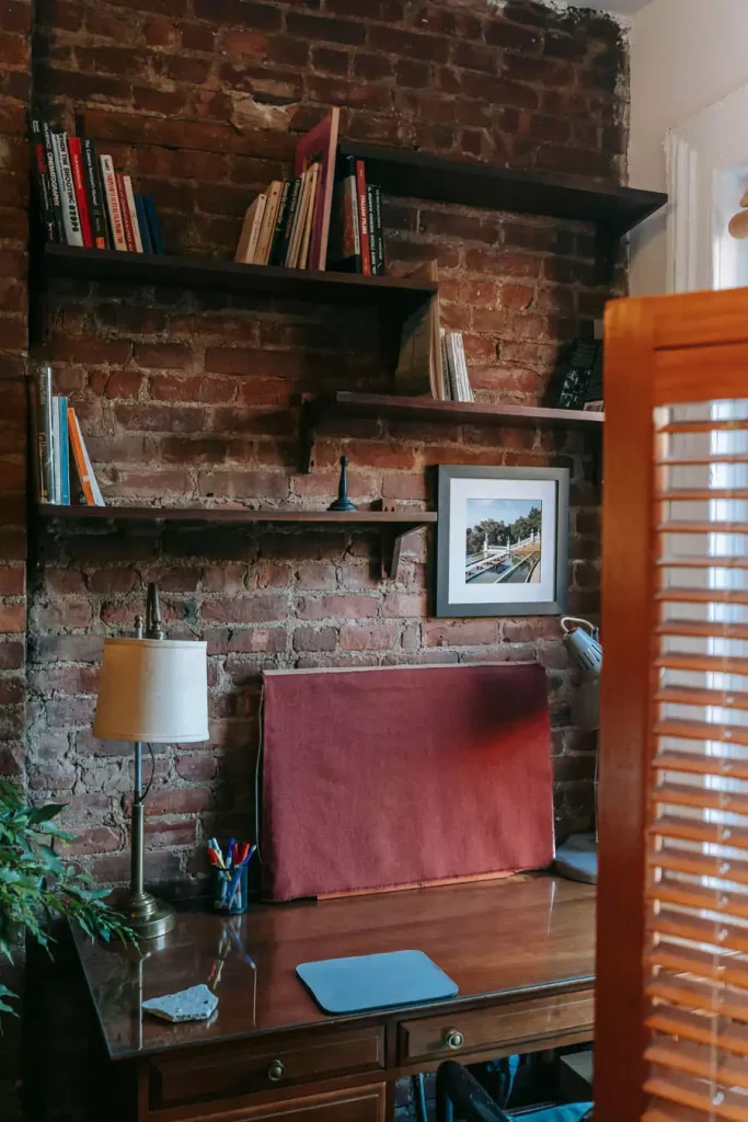 Study Room Bookshelves And A Framed Photograph On An Exposed Brick Wall Above A Wooden Writing Desk