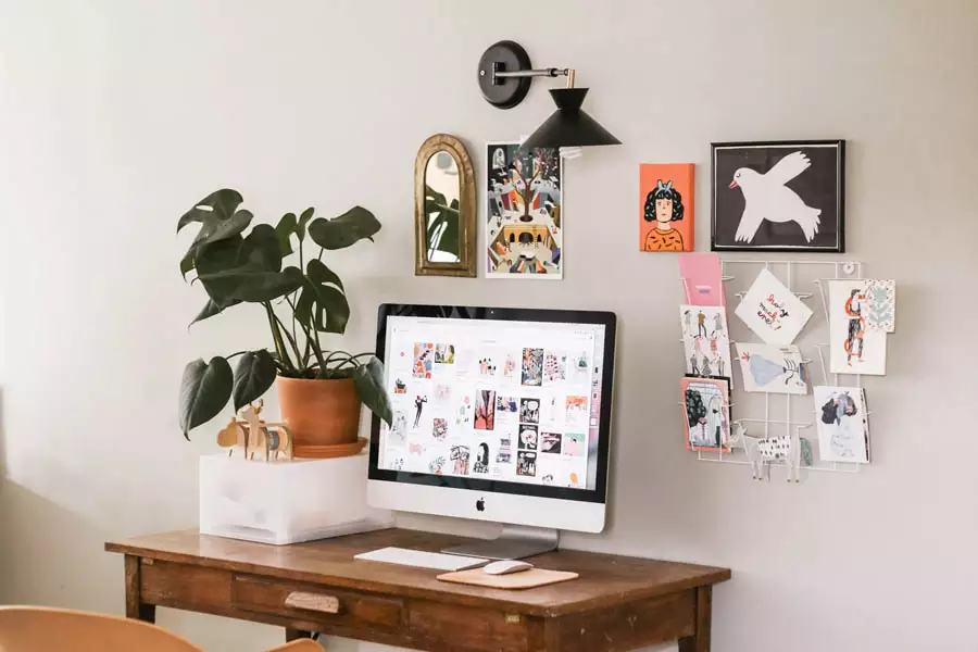 Study Wall Display With Small Framed Artworks An Arched Mirror A Wall Lamp And A Wire Memo Grid Above A Computer Desk