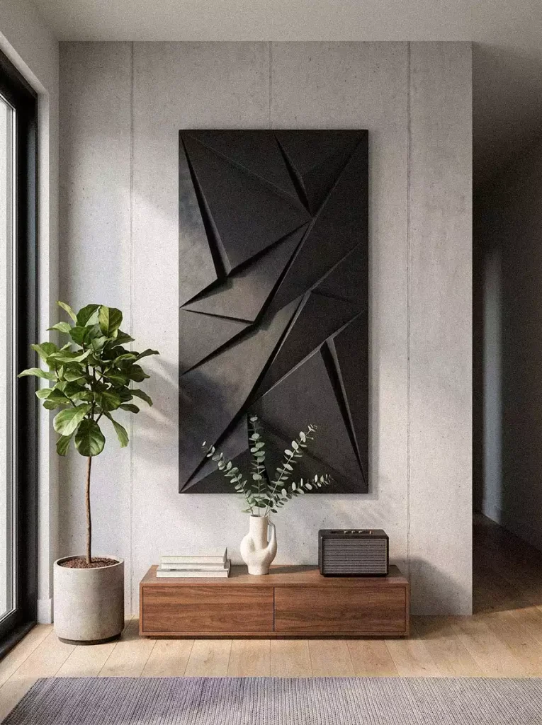 Tall dark geometric wall relief with overlapping angular planes above a low wooden cabinet