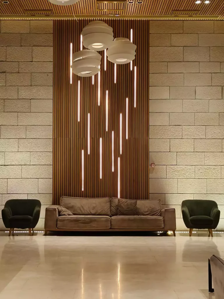 Tall wood slat feature wall with staggered vertical lights above a brown sofa