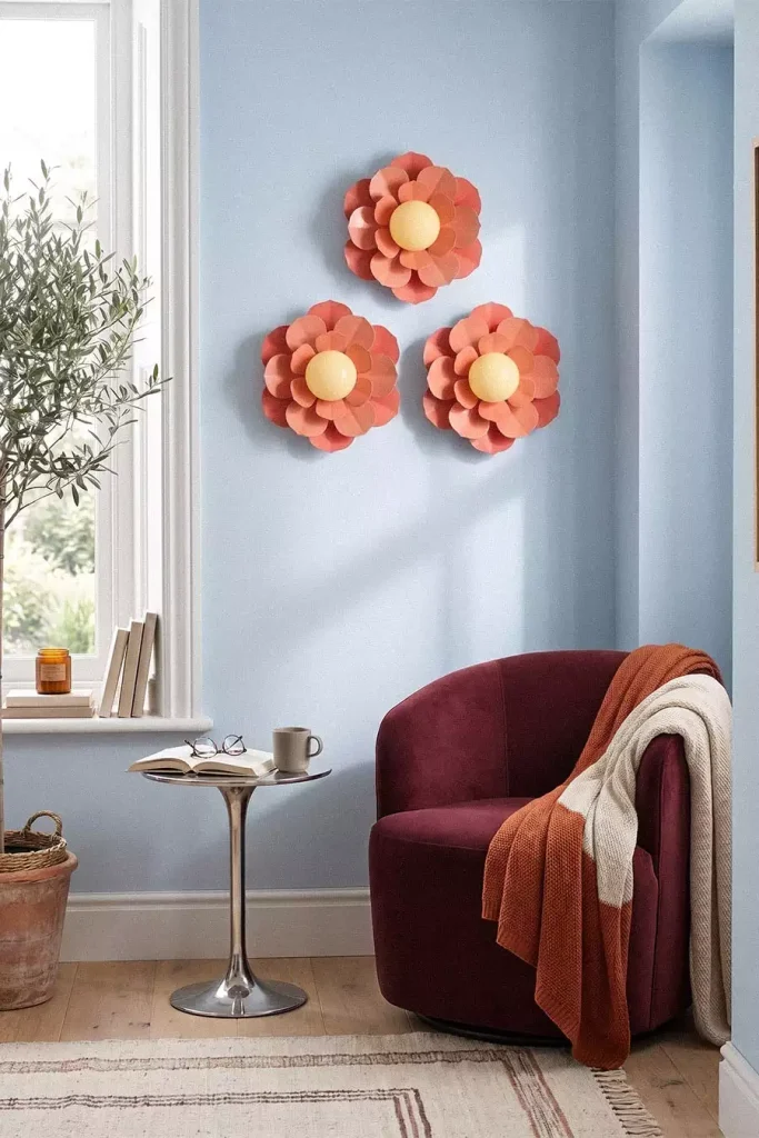 Three coral flower wall lights arranged in a triangle above a burgundy chair